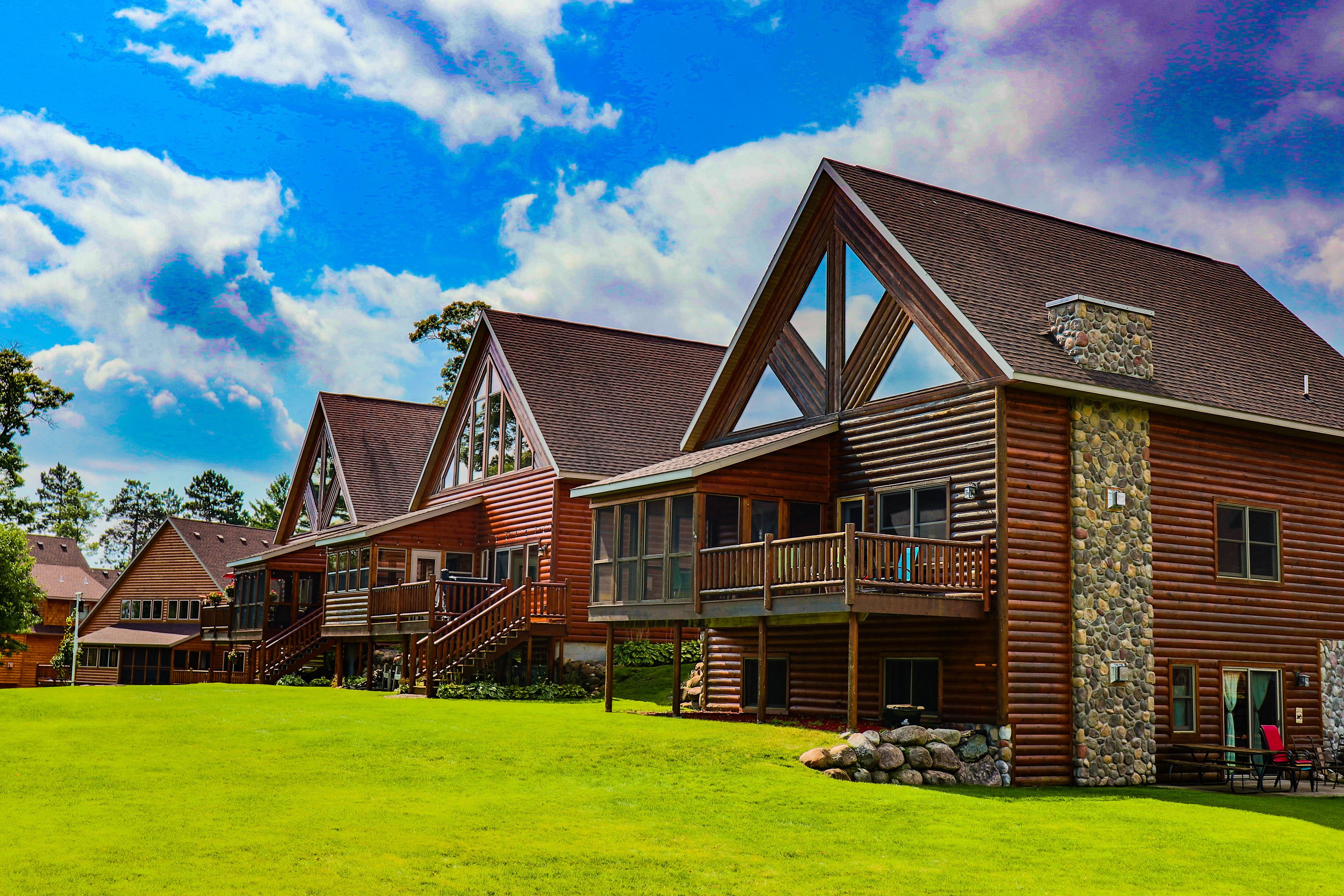 A large log cabin with multiple balconies and a stone chimney.