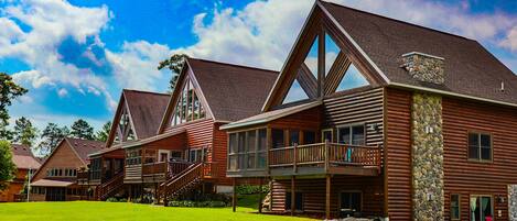 A large log cabin with multiple balconies and a stone chimney.