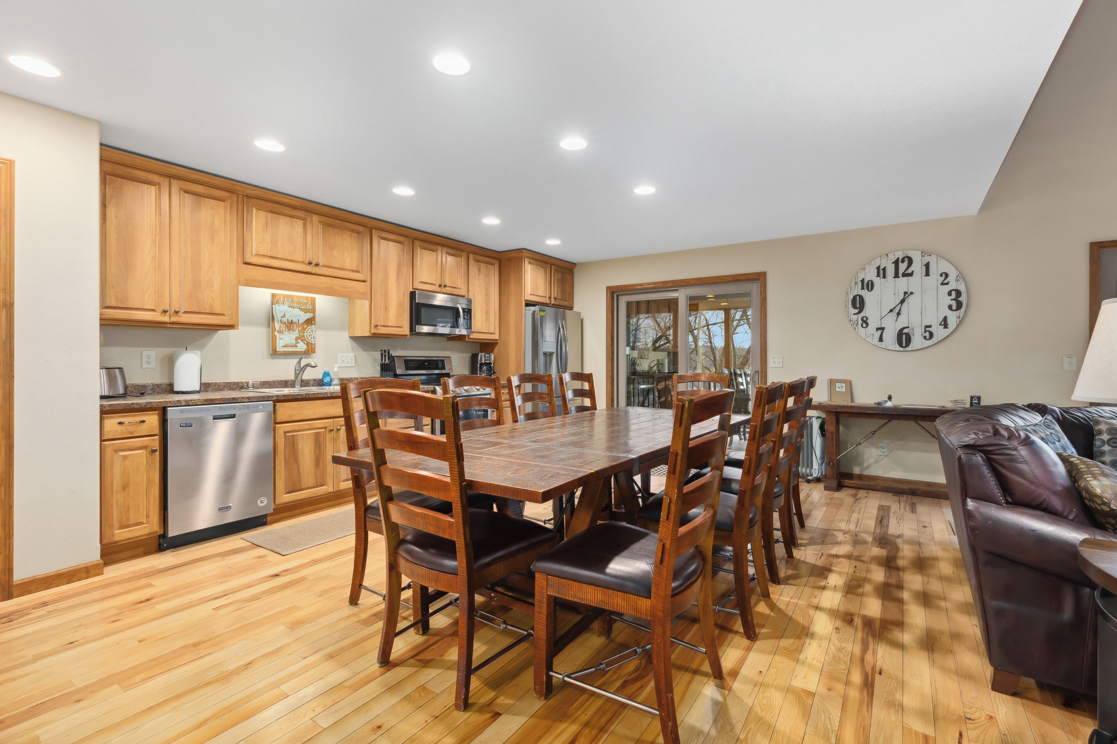 Una cocina moderna con armarios de madera, electrodomésticos de acero inoxidable y una zona de comedor con mesa y sillas de madera.