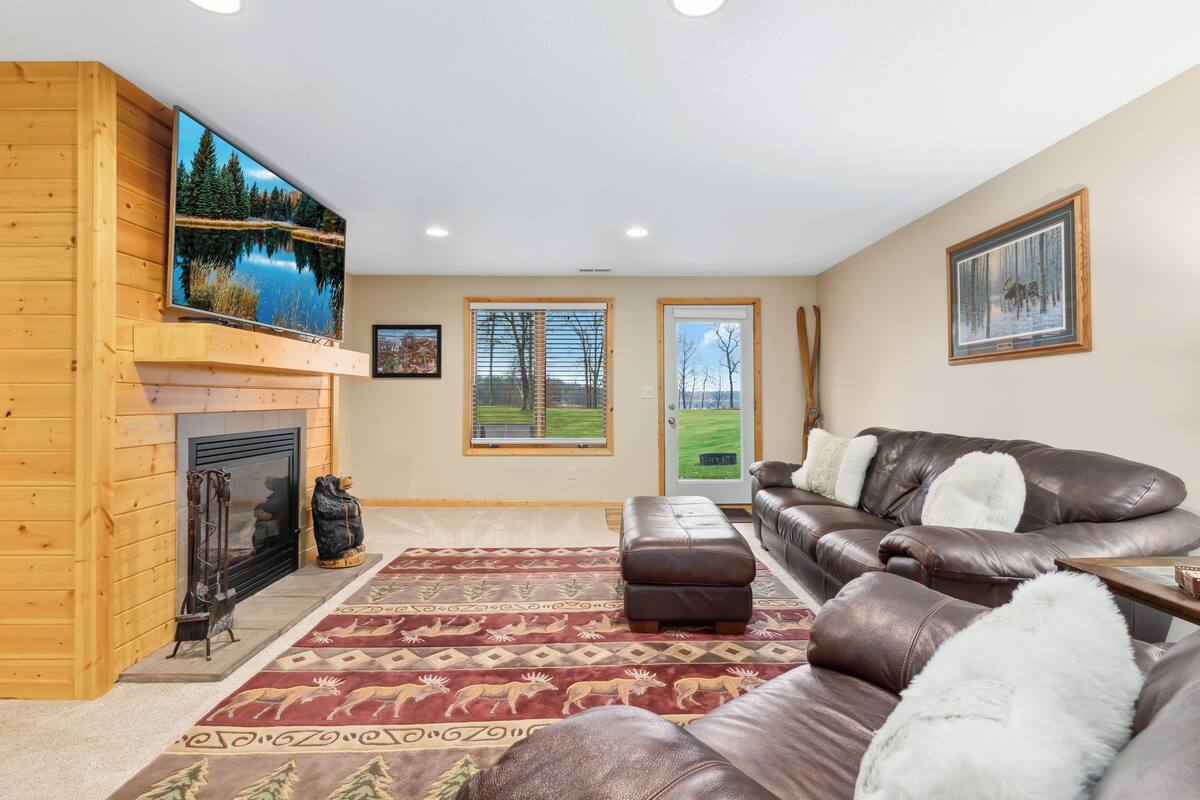 A living room with a fireplace, leather sofa, and a large TV.