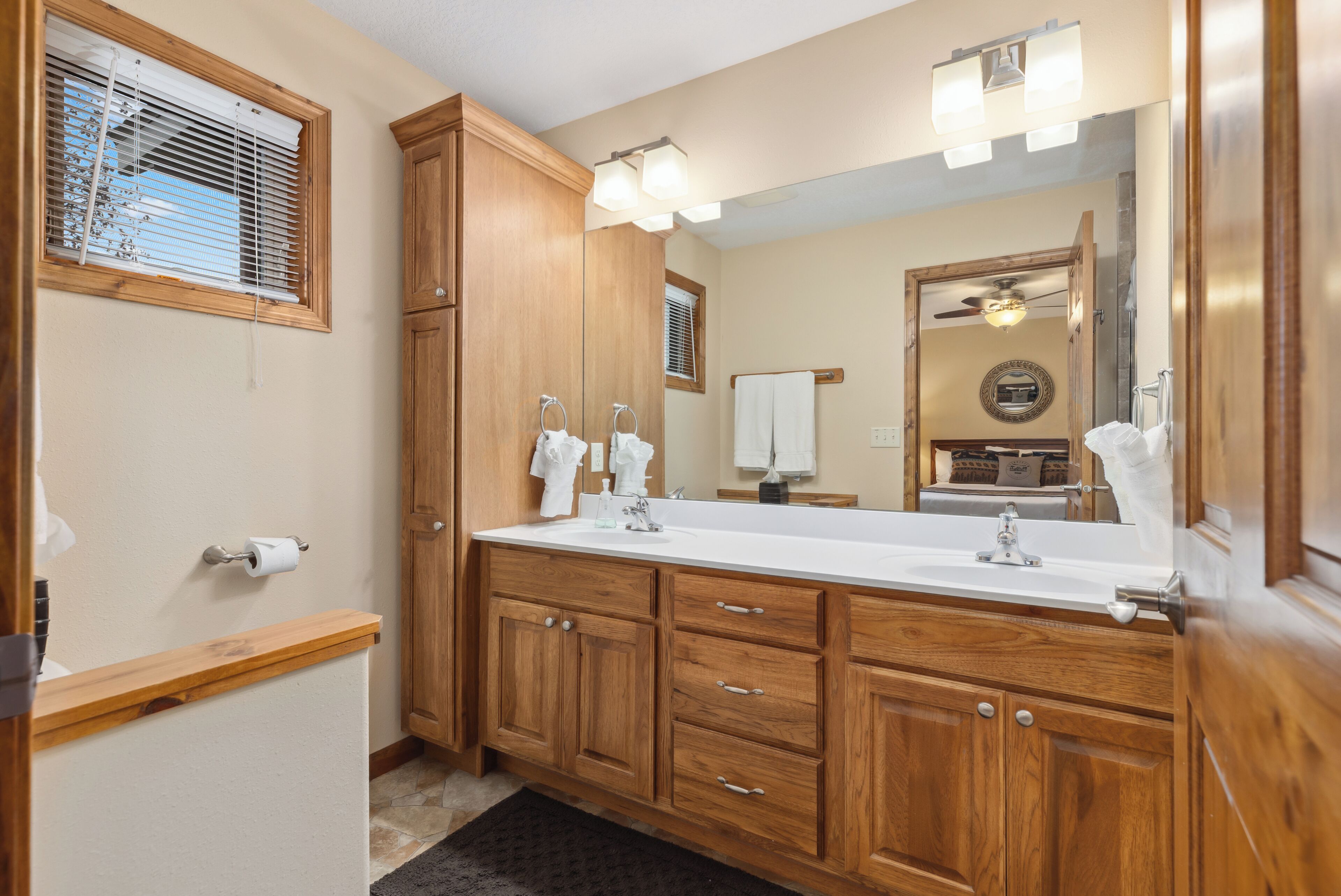 Un bagno con mobiletti in legno, uno specchio grande e un lavabo doppio.