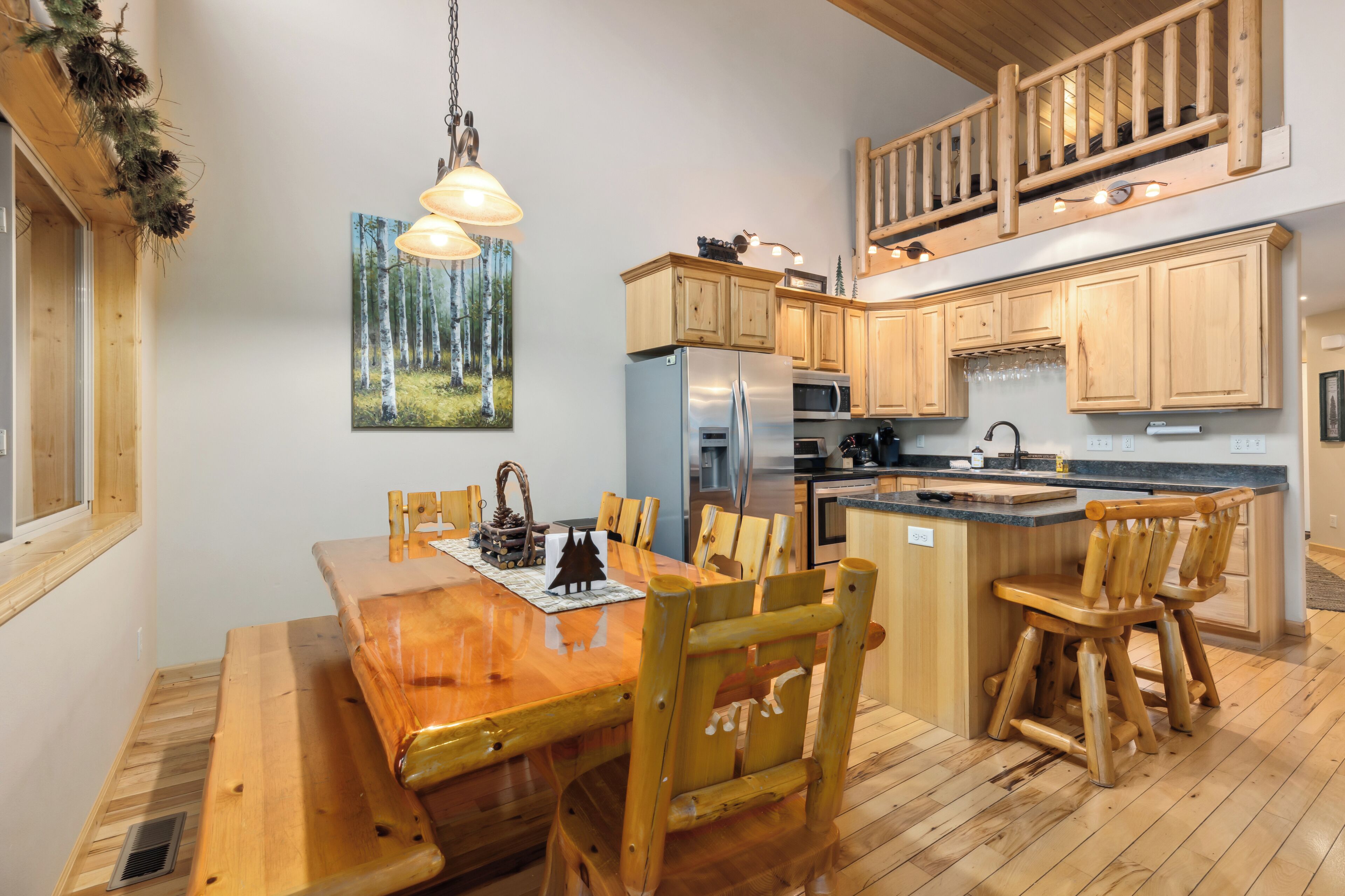 Une table à manger en bois avec des chaises, une cuisine avec des meubles en bois, un réfrigérateur et un four à micro-ondes.