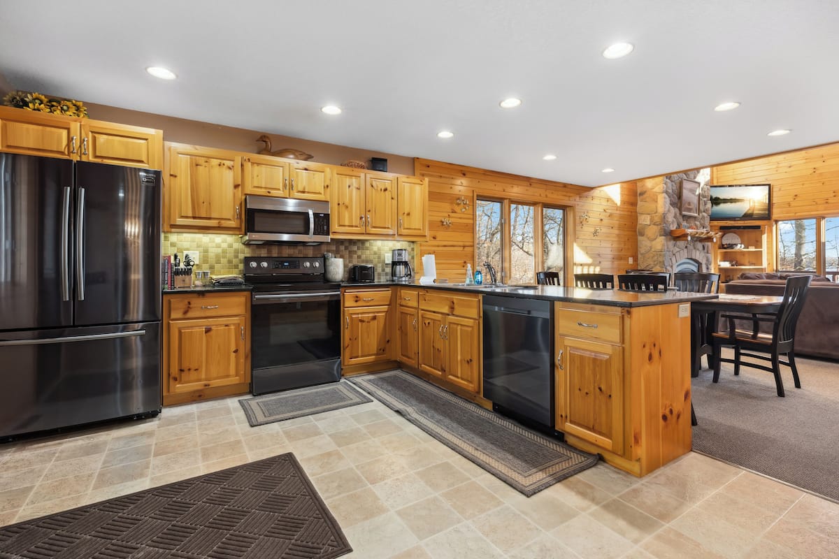A modern kitchen with wooden cabinets, stainless steel appliances, and a stone fireplace.