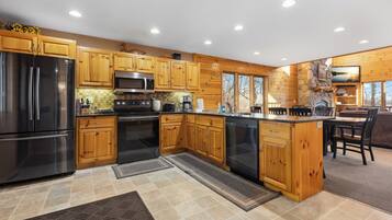 A modern kitchen with wooden cabinets, stainless steel appliances, and a stone fireplace.
