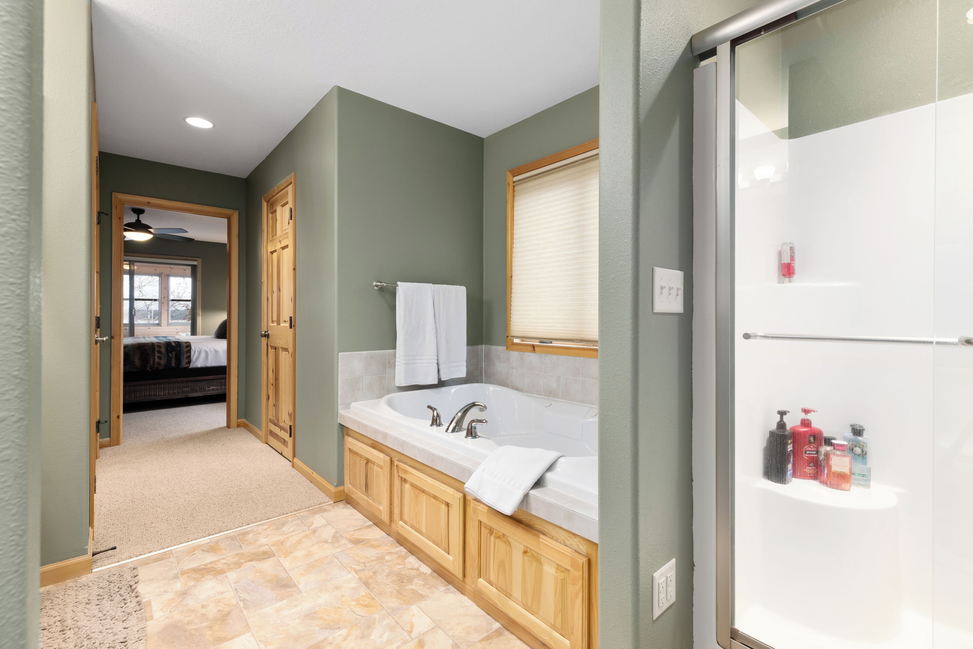 A bathroom with a large bathtub, wooden cabinets, and a shower area.