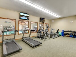 Un gimnasio con cintas de correr, elípticas y equipo de pesas.