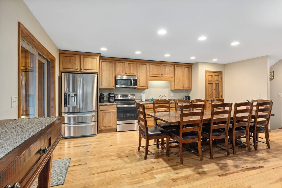 A modern kitchen with wooden cabinets, stainless steel appliances, and a dining area with a large table and chairs.
