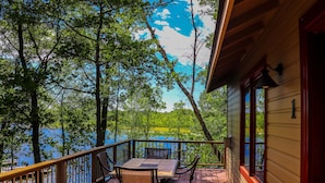 Une terrasse en bois avec une table et des chaises donnant sur un lac.