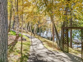 Un sendero pavimentado que atraviesa un área boscosa, con una estructura de madera a la derecha.