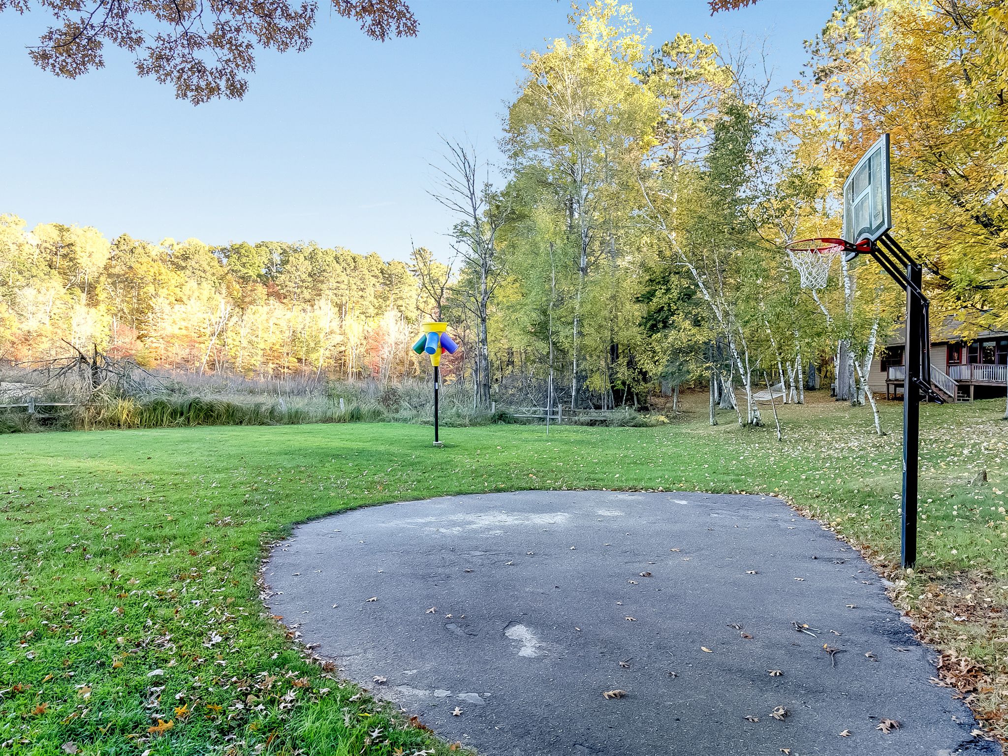 A basketball court with a hoop and a directional sign in a park.
