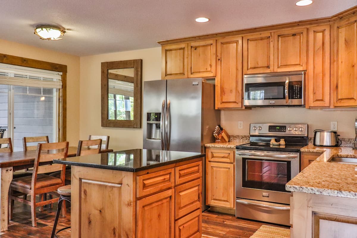 A kitchen with wooden cabinets, a stainless steel refrigerator, a microwave, and an oven.