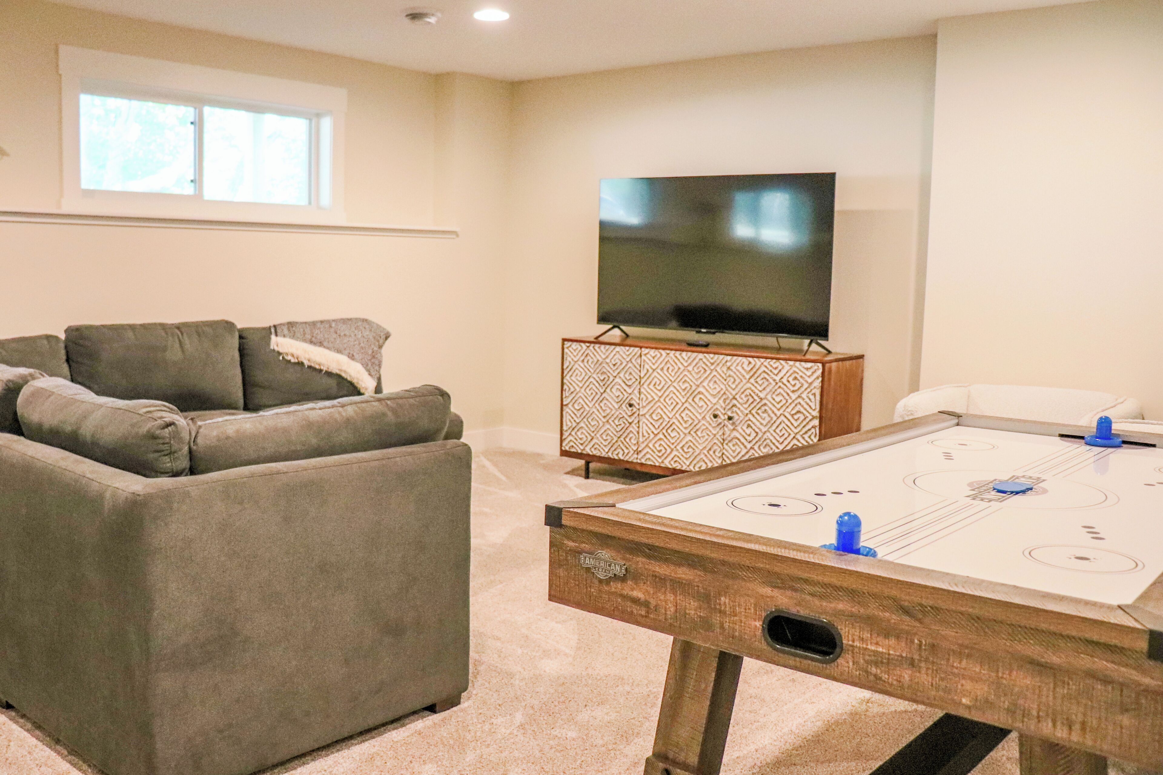 Una sala de estar con mesa de billar, un sofá, un televisor y un armario.