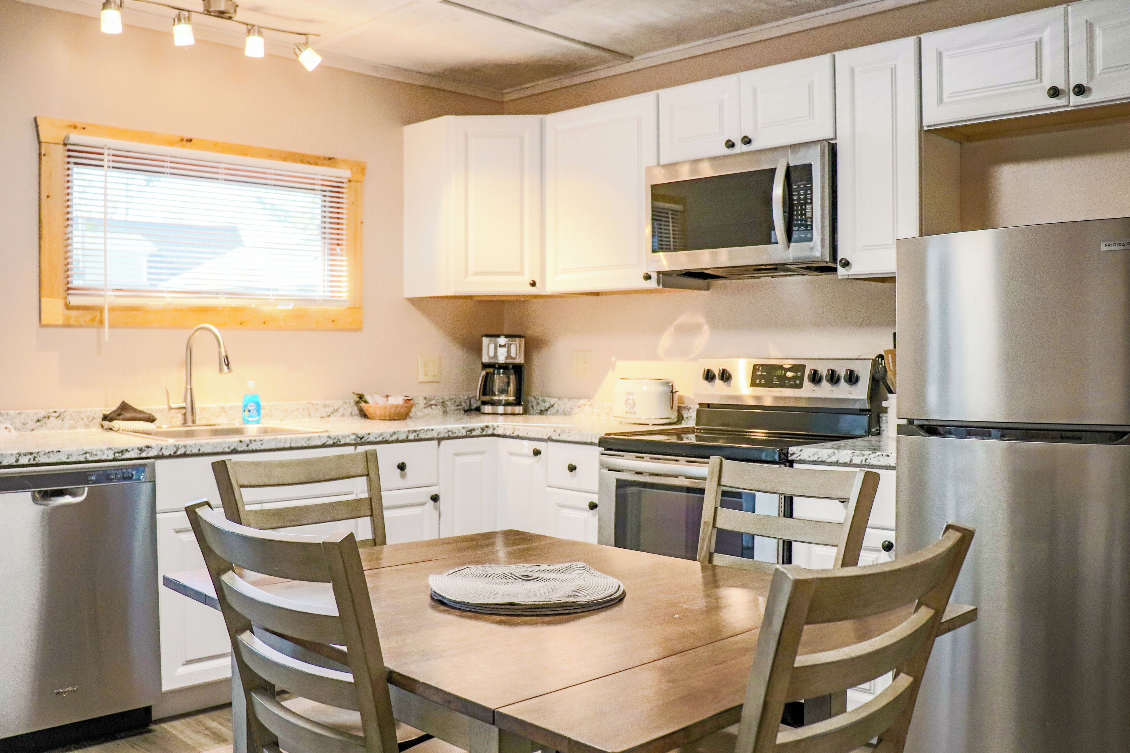 Una cocina moderna con armarios blancos, electrodomésticos de acero inoxidable y una mesa de comedor de madera.