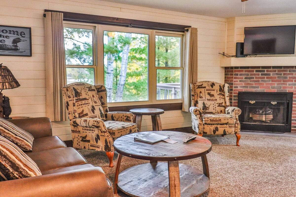 A cozy living room with patterned armchairs, a leather sofa, a round coffee table, and a fireplace.
