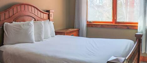 Una cama bien hecha con sábanas blancas y un cabecero de madera en una habitación con ventana.