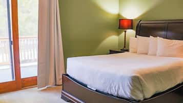 Une chambre à coucher comprenant un lit, une table de chevet, une lampe et une vue sur l’extérieur grâce à une porte coulissante.