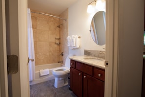 A bathroom with a bathtub, toilet, and vanity with a mirror. - 2 Bedroom Kauai Vacation Rental (Kapaa)