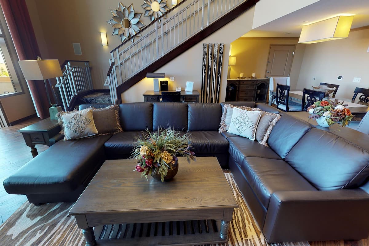 A modern living room with a sectional sofa, a wooden coffee table, and a staircase leading to an upper level.