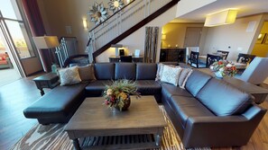 A modern living room with a sectional sofa, a wooden coffee table, and a staircase leading to an upper level.