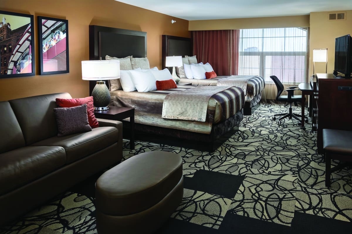 A hotel room with a large bed, a sofa, a desk, and a TV.