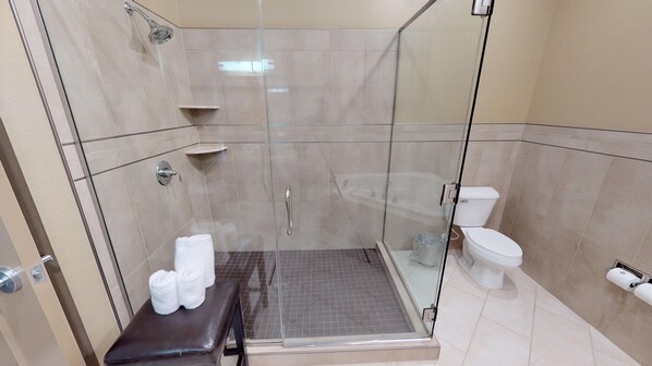 A glass-enclosed shower area with a toilet and a small sink.