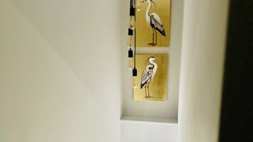 Una escalera con una lámpara moderna y dos cuadros de pájaros colgados en la pared.