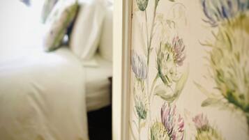 A bedroom with a bed, pillows, and a floral wallpaper.