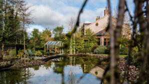 A serene garden with a pond, a greenhouse, and a traditional stone house. - Blackwell House (Craigavon)
