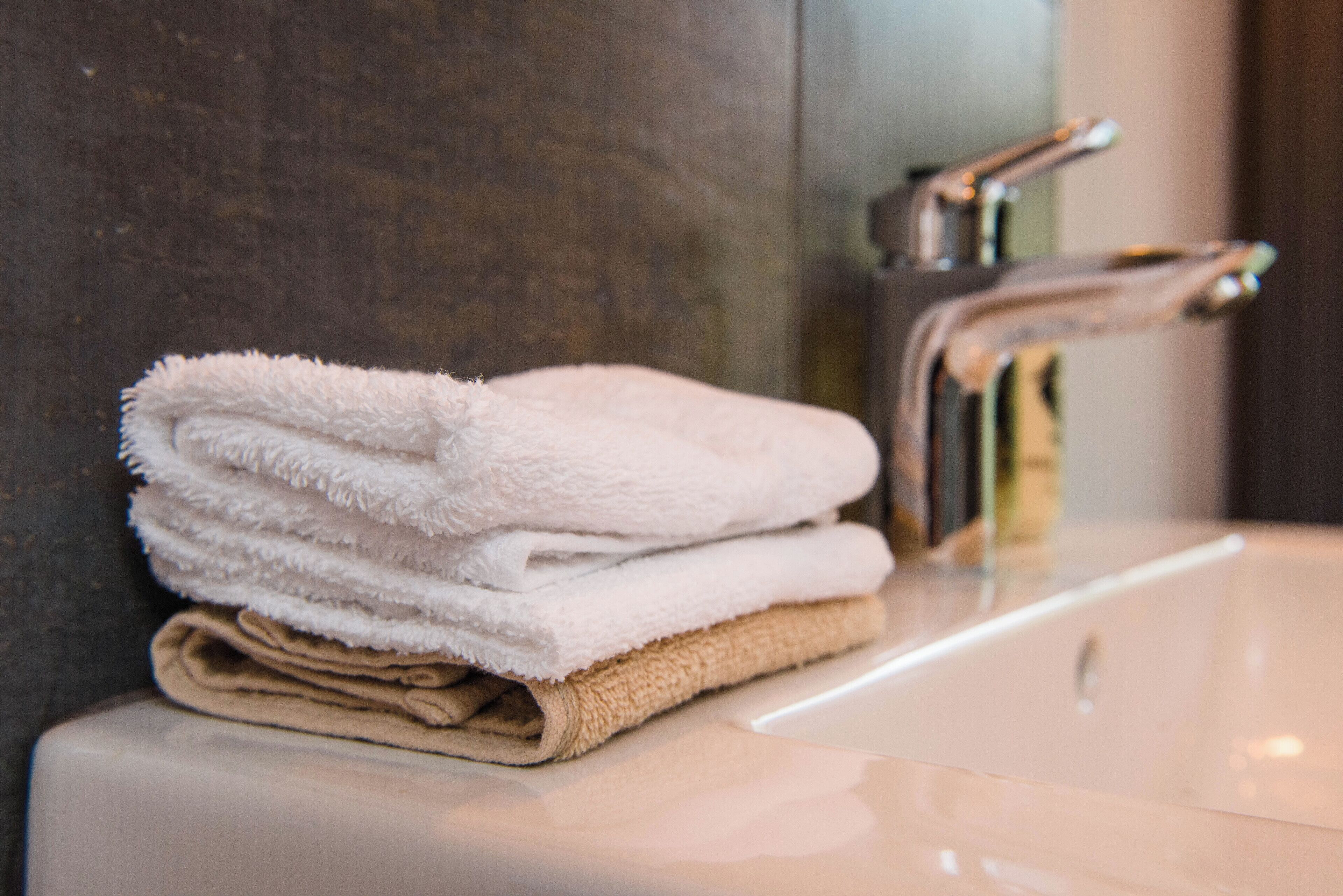 A stack of folded towels on a bathroom sink.