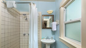 A bathroom with a shower, a sink, and a window. - River Rock Inn (Mariposa)