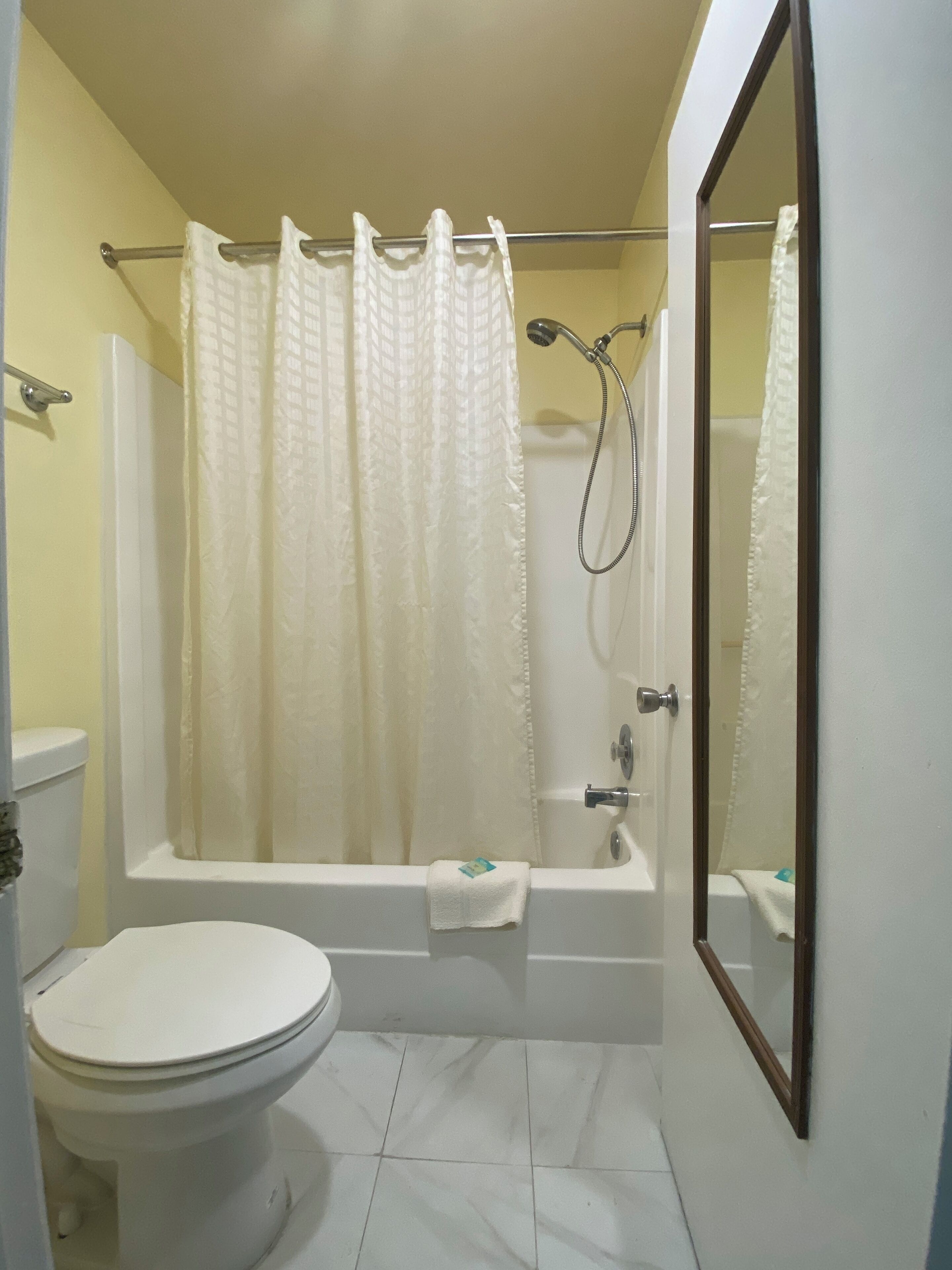 Un baño con bañera, inodoro y cortina de ducha.