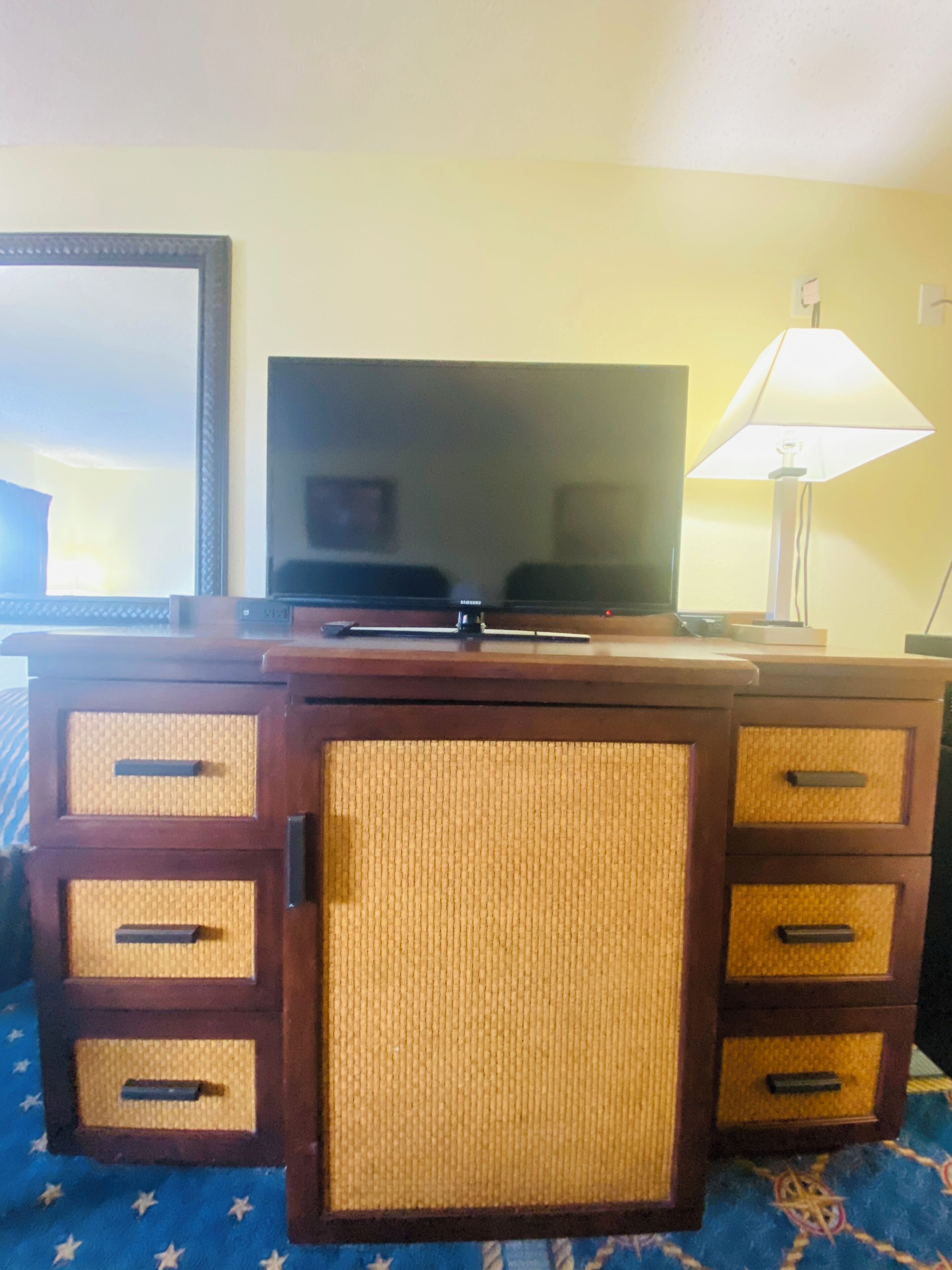 A wooden cabinet with woven storage compartments and a television on top.