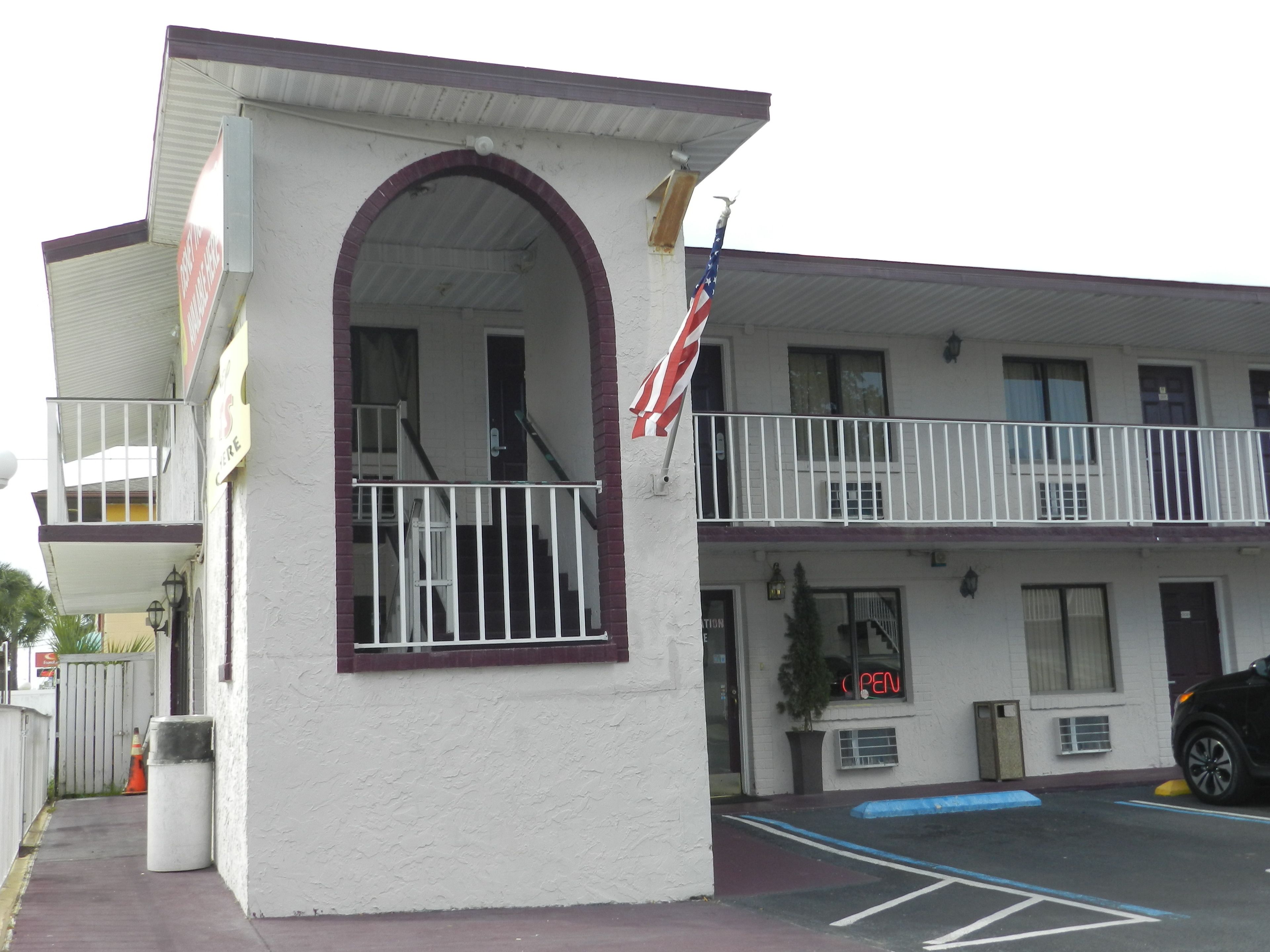 Ein Motel mit weißer Fassade, einem Balkon mit Geländer und einer amerikanischen Flagge.