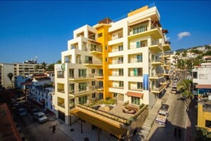 Un hotel de varios pisos con balcones, un patio central y vistas del área urbana circundante.