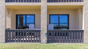 A building with two balconies, each with a table and chairs, and large windows offering a view of the ocean. - The Tiki (South Padre Island)
