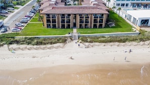 A beachfront hotel with a central courtyard, a parking lot, and a sandy beach area. - The Tiki (South Padre Island)