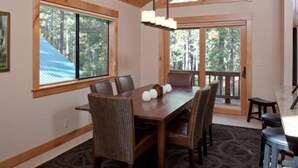 Uma sala de jantar com uma mesa de madeira, cadeiras e um lustre.