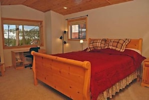 A bedroom with a wooden bed, a desk, and a window with a view of trees and mountains. - Comfortable Stockholm Vista (Truckee)