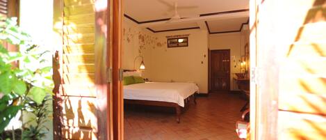 A bedroom with a bed, a ceiling fan, and a window.