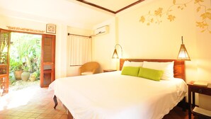 Habitación de hotel con una cama grande, una silla, una mesita de noche y una ventana con cortinas.
