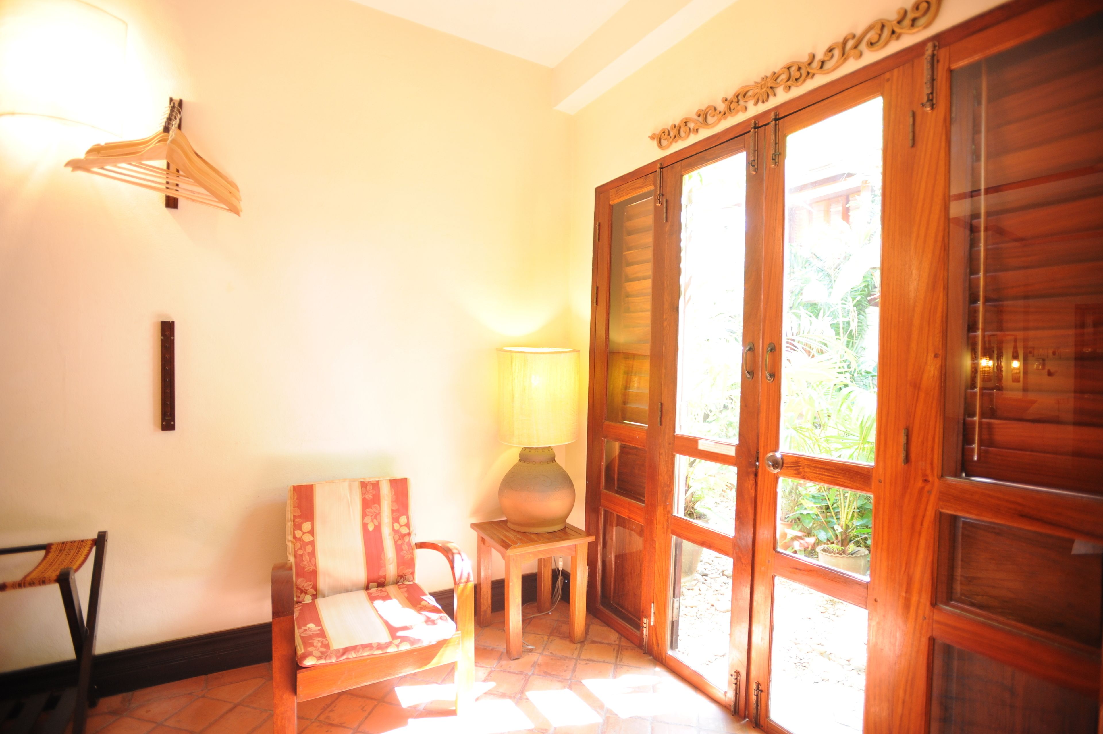 A room with a wooden door, a lamp, a chair, and a wall-mounted rack.