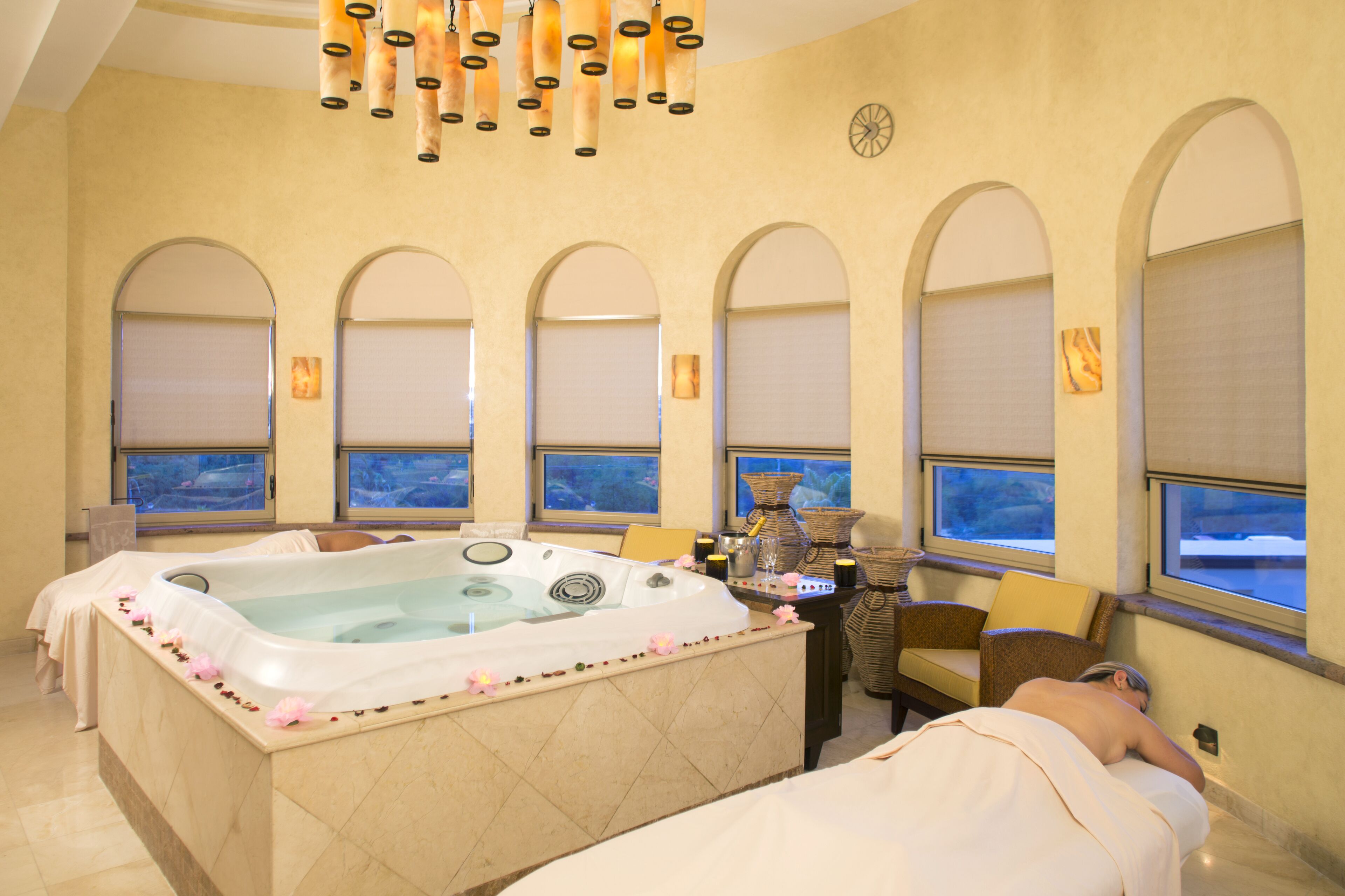 A spa room with a large bathtub, arched windows, and a view of the outdoors.