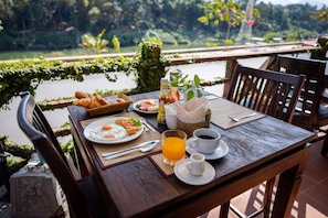 Enjoy a leisurely breakfast on the outdoor terrace with a view of the lush garden and serene water feature.