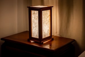 A traditional-style lantern adds warmth to the room, complemented by a nightstand against a wall with a sheer curtain.