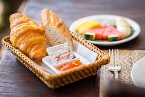 Enjoy a delicious breakfast with a wicker basket filled with fresh pastries and fruit.