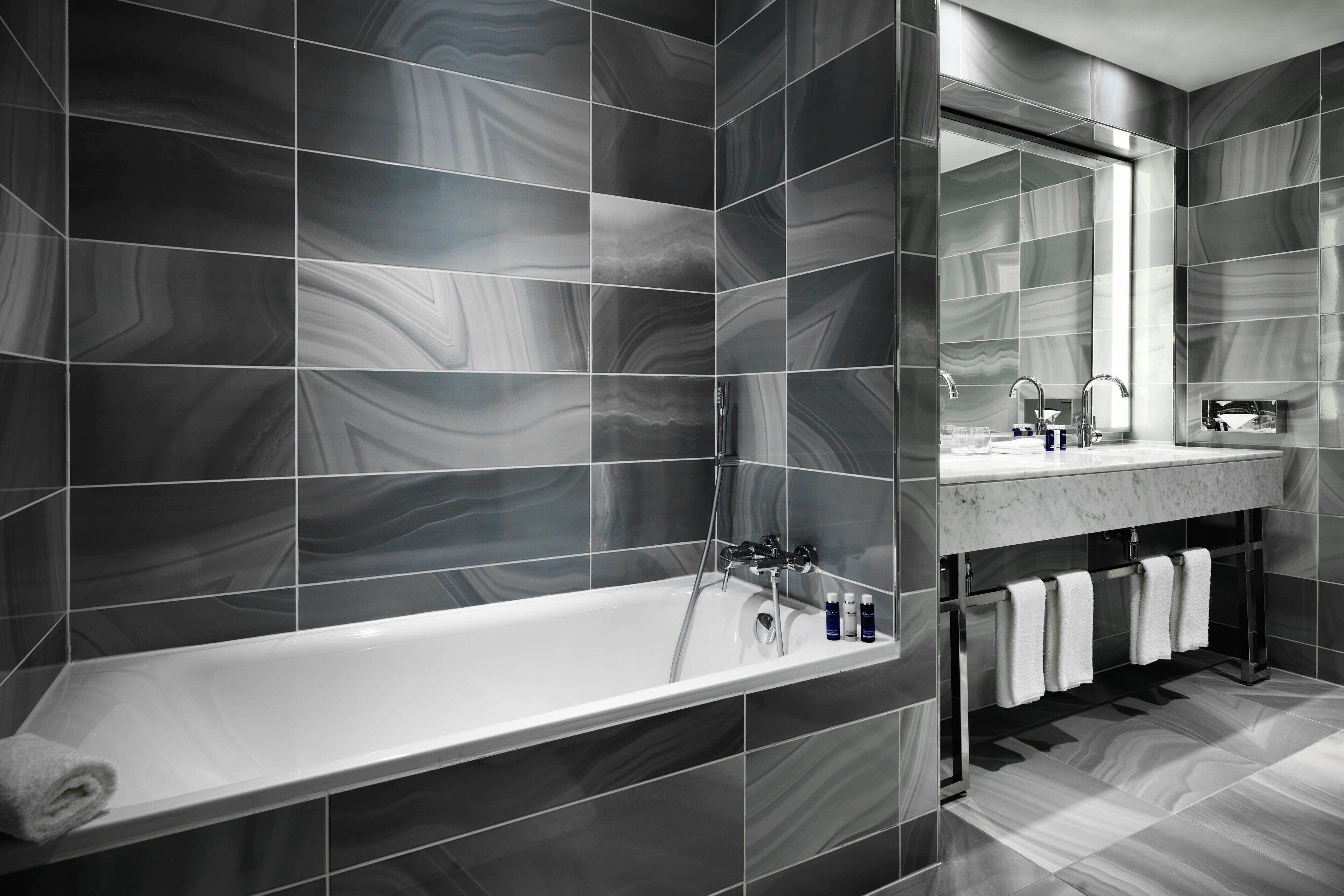 A modern bathroom with a large bathtub, a vanity with a mirror, and a towel rack.