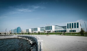 Un ensemble immobilier moderne avec vue sur le front de mer, comprenant un pont et un espace paysager agrémenté de bancs.