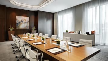 A conference room with a long table, chairs, and a painting on the wall.