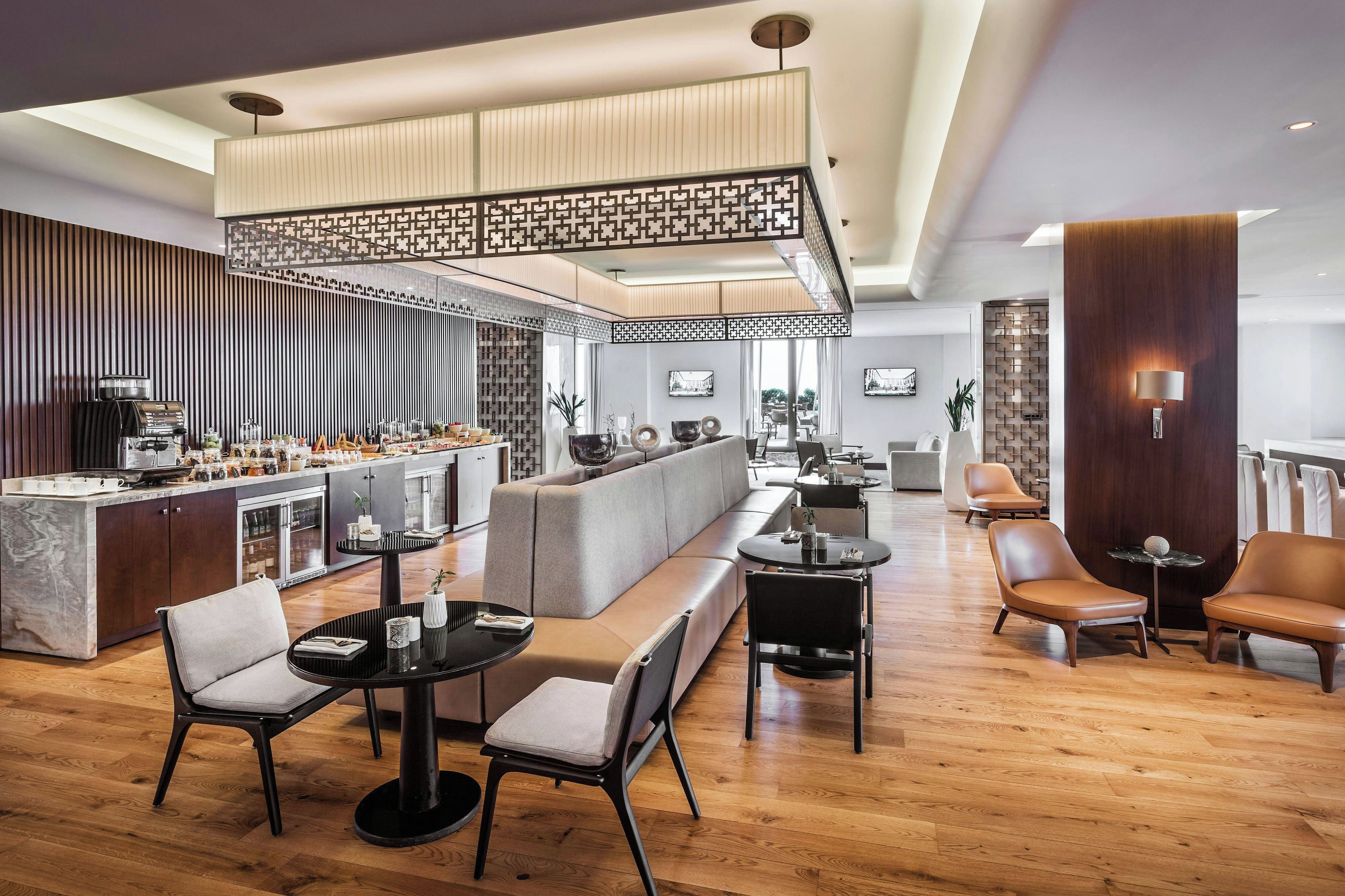 A modern hotel lobby with a bar area, seating arrangements, and a view of the outdoors.