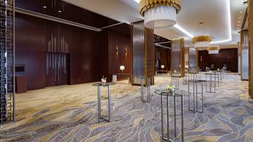 A spacious hotel lobby with a patterned carpet, modern furniture, and decorative lighting fixtures.